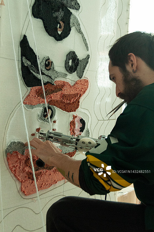 30岁西班牙裔拉丁胡须男子在工作室制作手工簇绒地毯图片素材