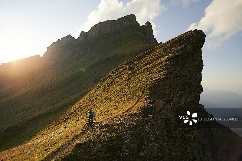 山地自行车手在高山草甸的狭窄小路上行驶图片素材