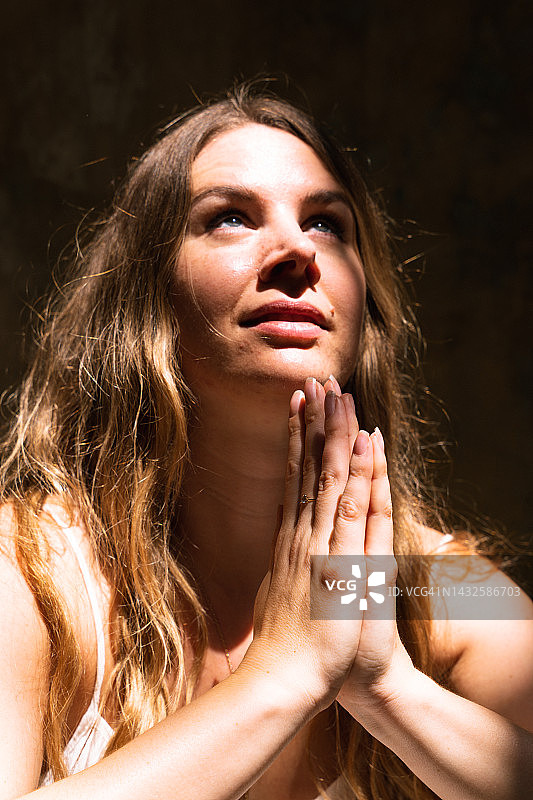 合十手势的女子光影肖像图片素材