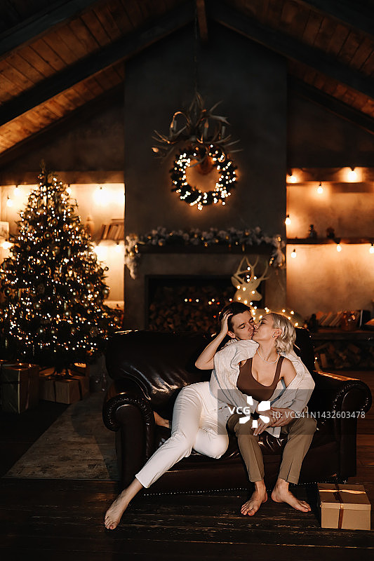情侣在乡村小屋的壁炉旁拥抱亲吻，庆祝圣诞节图片素材