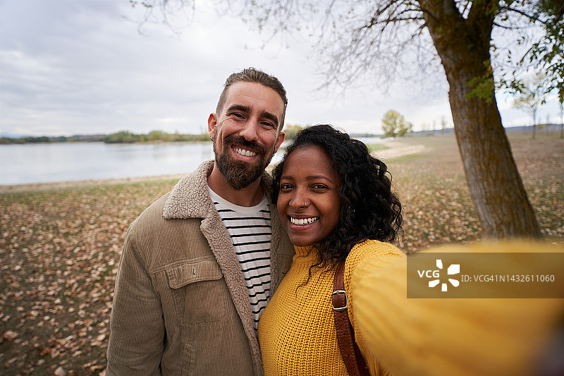 一对年轻情侣在湖边自拍的秋季照片图片素材