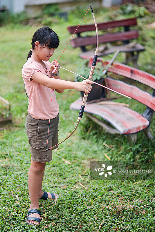 女孩尝试射自己制作的竹弓图片素材
