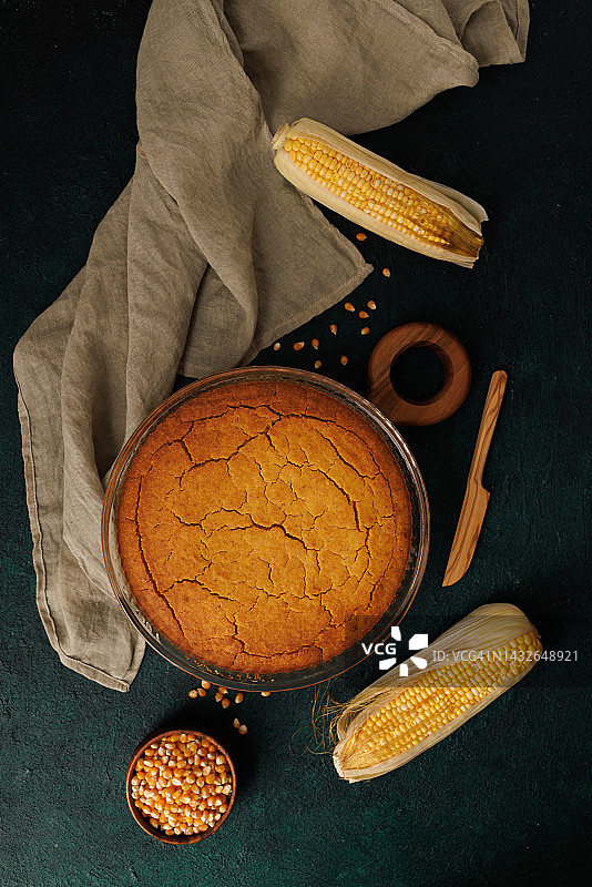 深蓝绿色粗糙背景上的新鲜出炉的圆形玉米面包图片素材