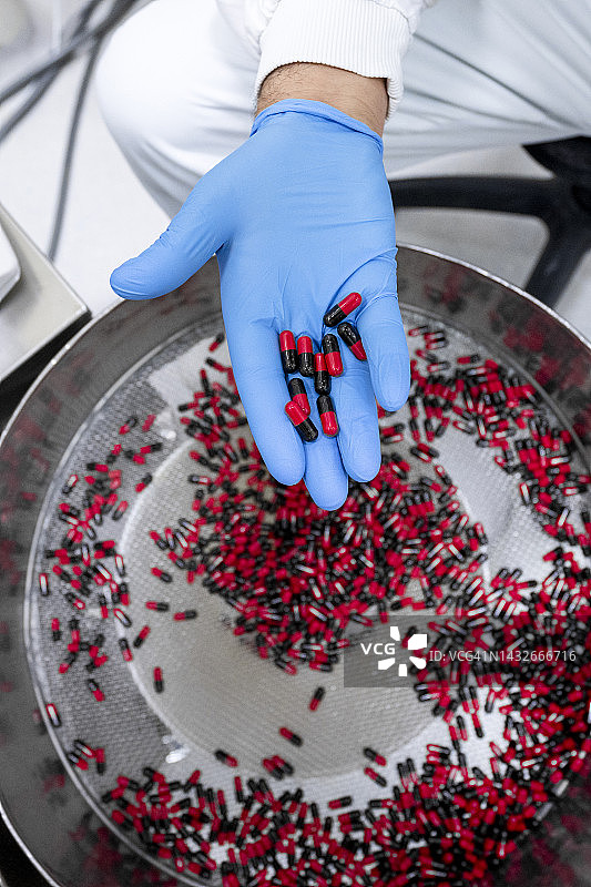 制药厂实验室里男人手拿药丸特写图片素材