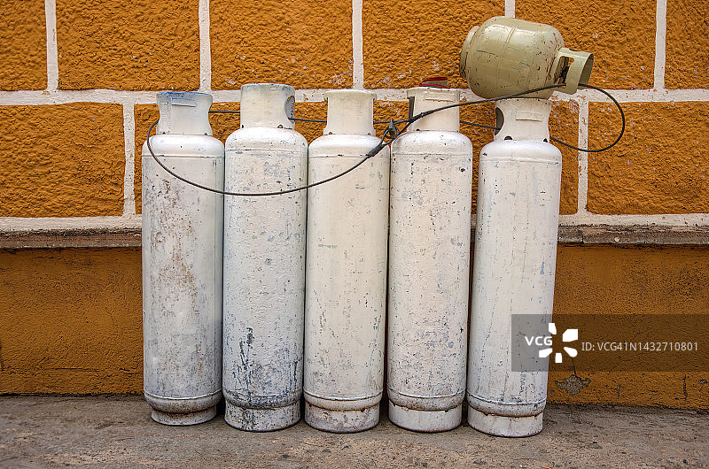 用链子拴在一起的、可再填充的空煤气罐，靠在殖民建筑的外墙上图片素材