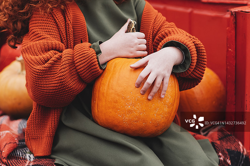 白人少女在秋日公园手捧橘色北海道南瓜遮面肖像照图片素材