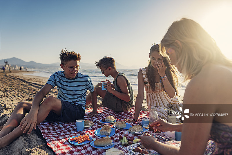 在海滩上享用夏季野餐早餐的家庭图片素材