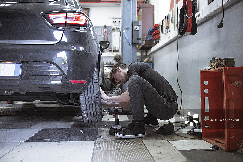 在小型汽车修理店更换轮胎图片素材
