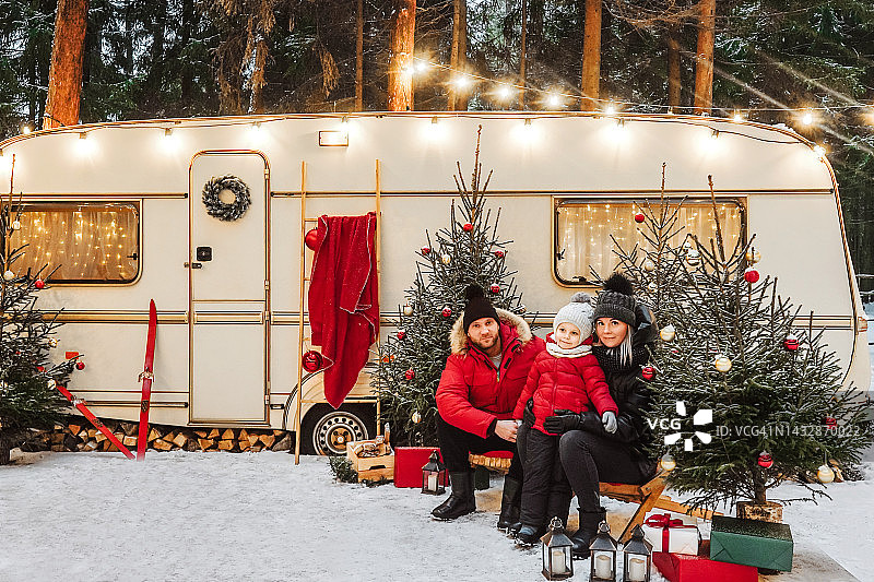 幸福的一家人在冬季装饰过的房车附近度过美好时光。图片素材