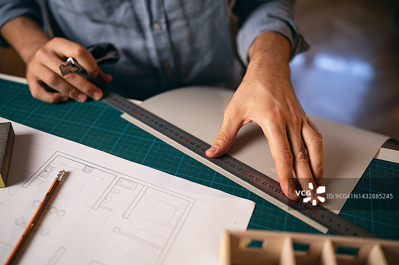 建筑师用尺子测量纸张，同时制作建筑模型图片素材
