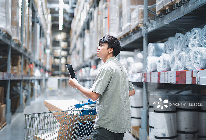 亚洲男人在购物中心用平板电脑购物图片素材