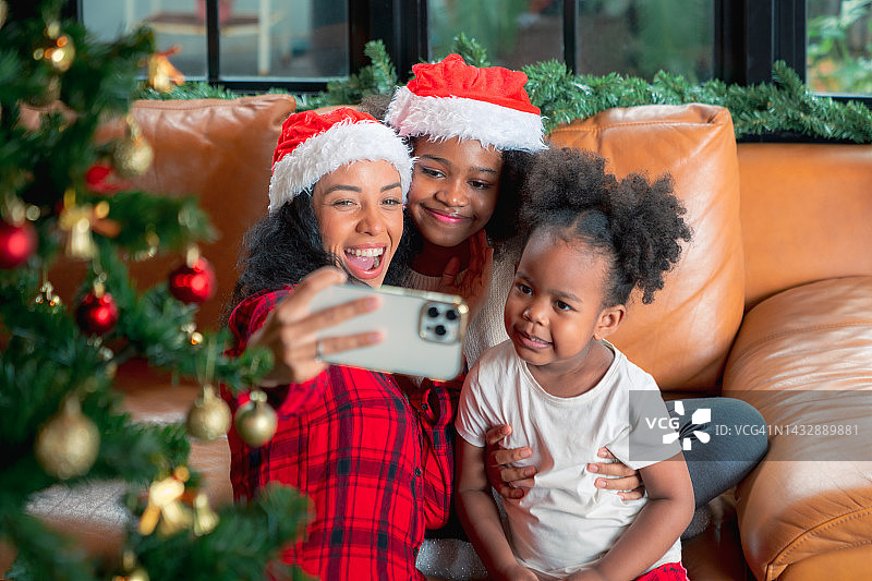 幸福的一家人戴着圣诞老人助手帽用相机拍照。家庭、圣诞节、冬季、幸福和人物概念图片素材