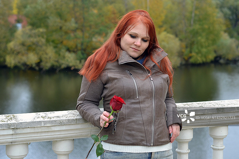 年轻女子在公园里手持红玫瑰图片素材