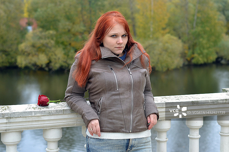 年轻女子在公园里手持红玫瑰图片素材