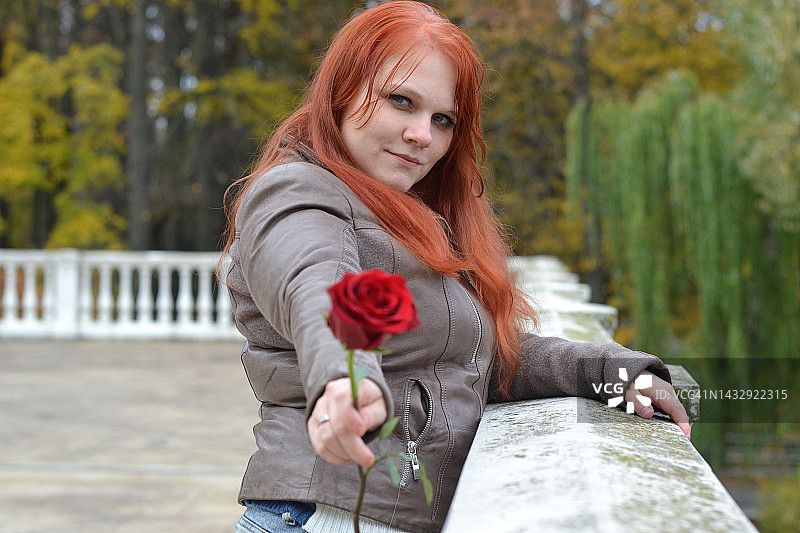 年轻女子在公园里手持红玫瑰图片素材