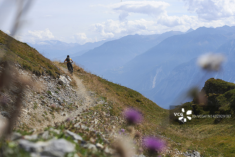 山地自行车手在山脊上骑行狭窄小径图片素材