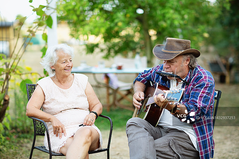 为妻子弹吉他和口琴的年长男人图片素材