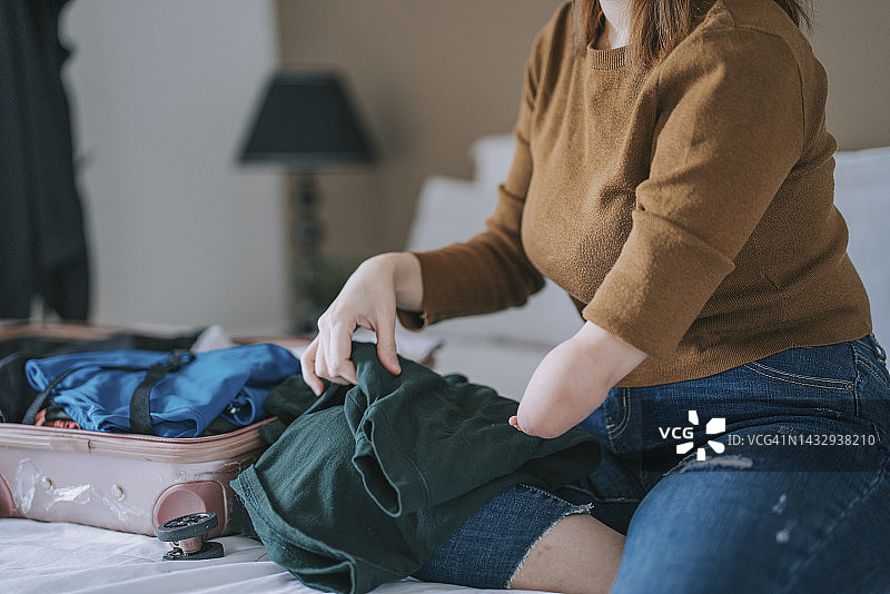 手臂截肢的华裔女性在卧室整理行李准备旅行图片素材