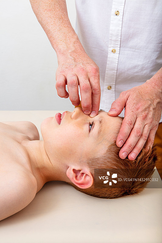 整骨医生触摸头部治疗一名年轻男孩图片素材