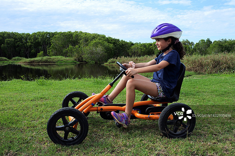 年轻女孩骑着脚踏式卡丁车户外玩耍图片素材