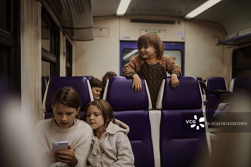 孩子们在火车车厢里用智能手机旅行图片素材