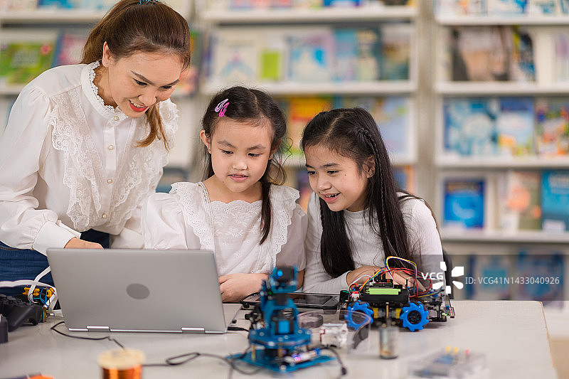 女教师在教室里向小学生讲解机械臂原型图片素材