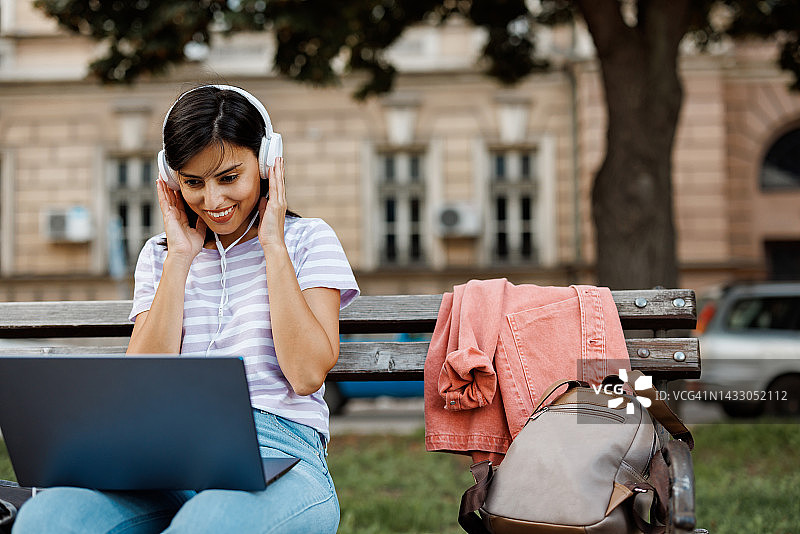 坐在校园长椅上用笔记本电脑学习的年轻女子图片素材