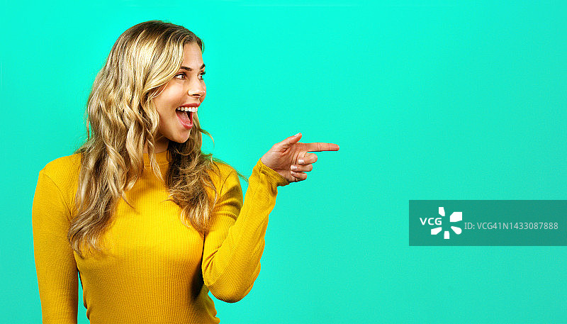 广告样机：快乐的女人指向绿色背景墙，用于营销、创意品牌宣传和促销活动。惊喜工作室微笑人物空白抽象图片素材