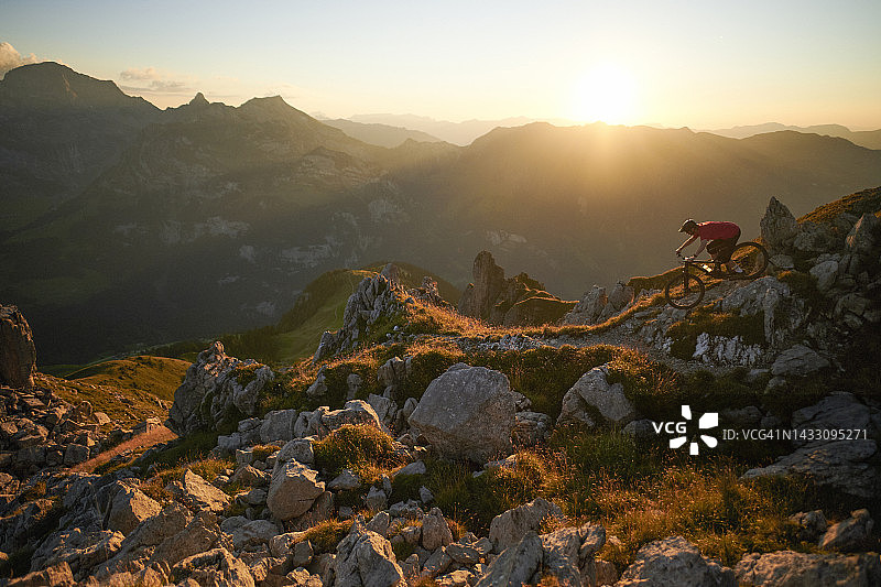 山地自行车手在日落时骑行在岩石小路上图片素材