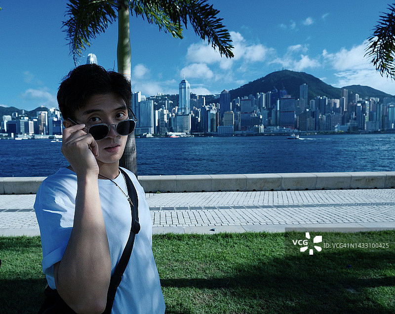 在维多利亚港前的亚洲青年男人图片素材