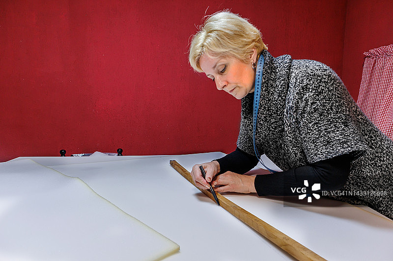 女裁缝在工作室用尺子准备布料图片素材