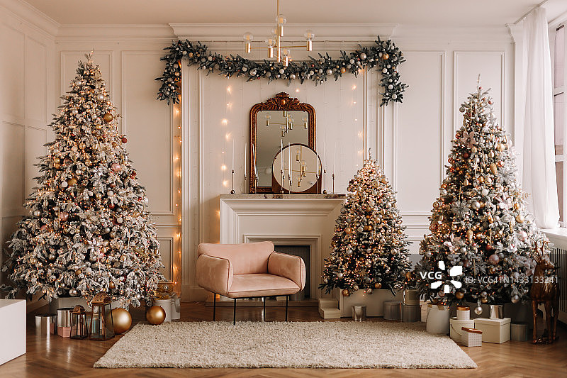 圣诞节概念：奢华现代风格的节日圣诞内饰，配有壁炉，并装饰有圣诞球和圣诞树花环图片素材