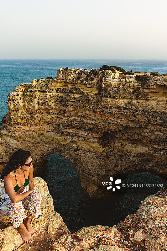 坐在悬崖边，背景是独特岩石构造的女人图片素材