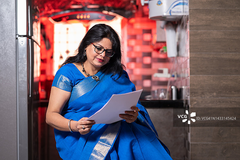 在办公桌前检查文件的中年妇女图片素材