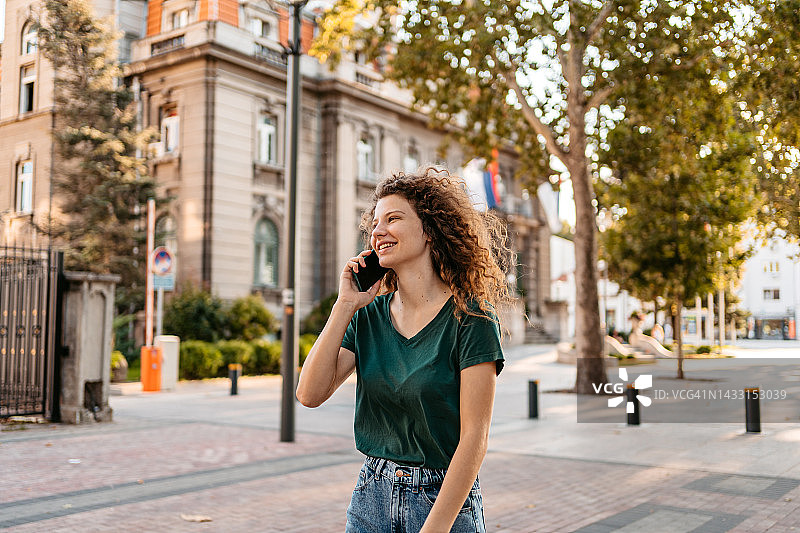 年轻女子在街上边走边打电话图片素材