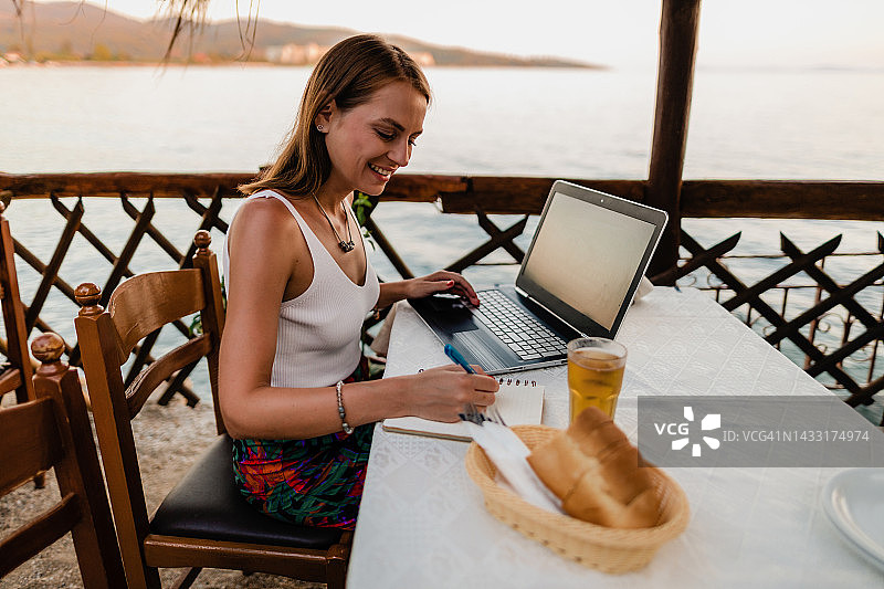 在希腊海边餐厅学习的年轻女人图片素材