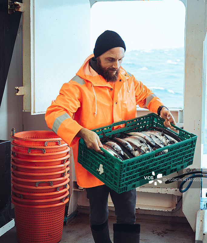 渔船甲板上放着新鲜鱼箱的渔夫图片素材