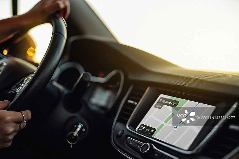 女人手在驾驶时握着带有GPS导航的汽车方向盘图片素材