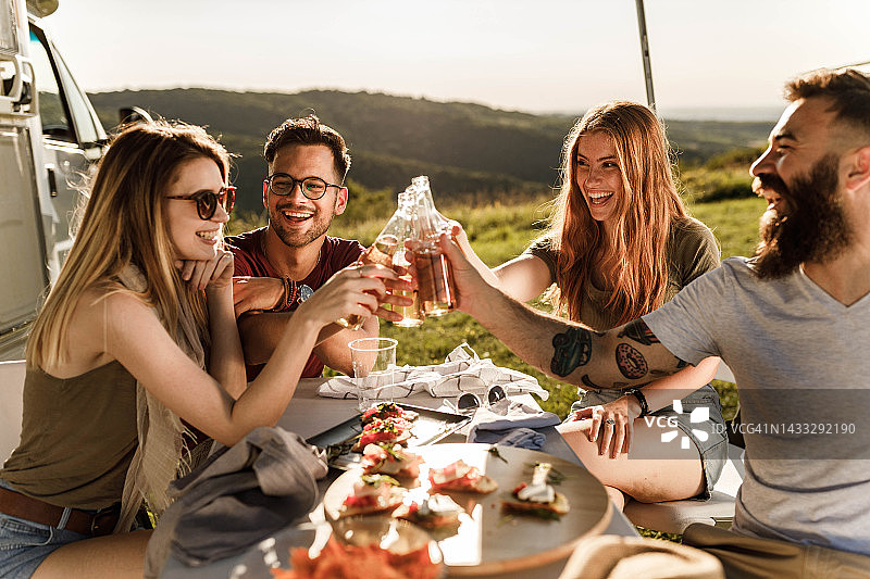朋友们在野外露营时愉快地喝啤酒图片素材