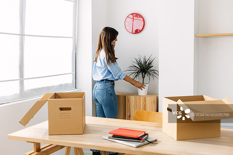 年轻女商人开始新工作，在办公室摆放植物 - 创业概念图片素材