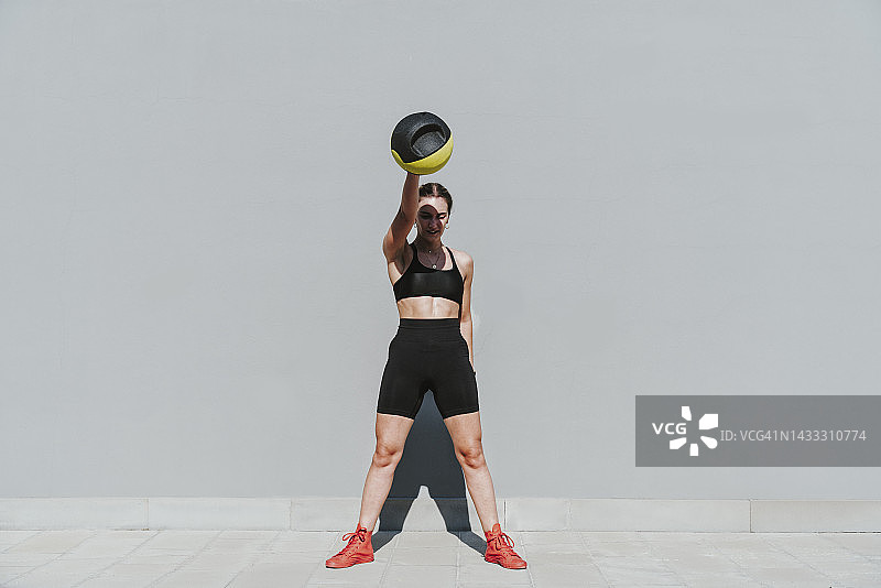 在灰色墙壁前用药球锻炼的年轻运动员图片素材