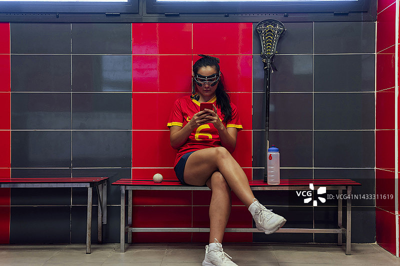 球员坐在长曲棍球更衣室里使用智能手机图片素材