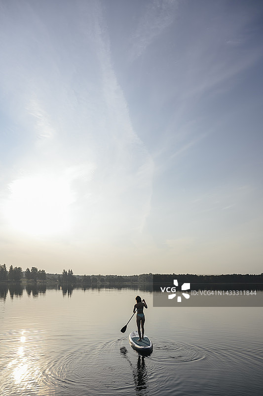 女人在湖中划桨板图片素材