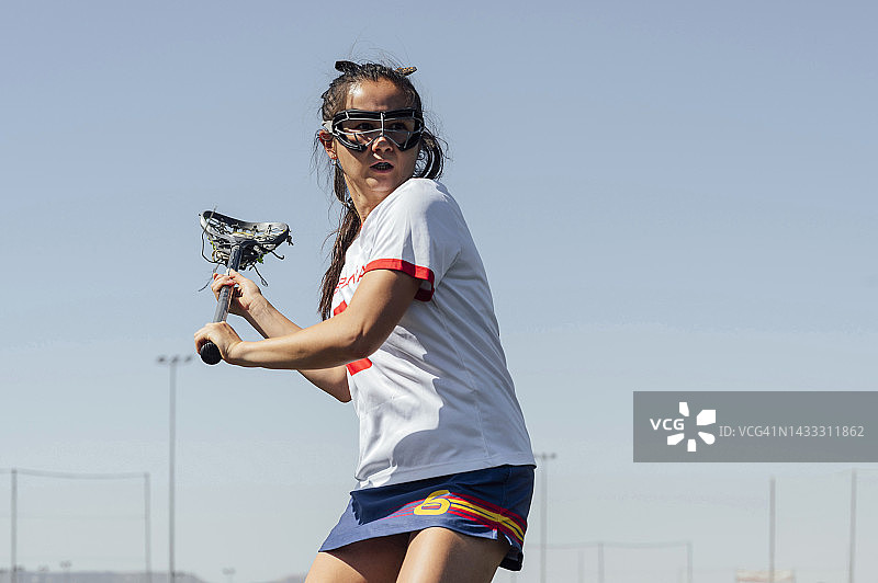 在晴朗天空下打长曲棍球的运动员图片素材