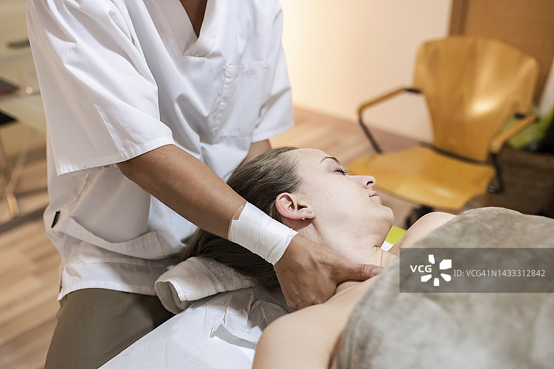 女子在水疗中心接受女按摩师的按摩图片素材