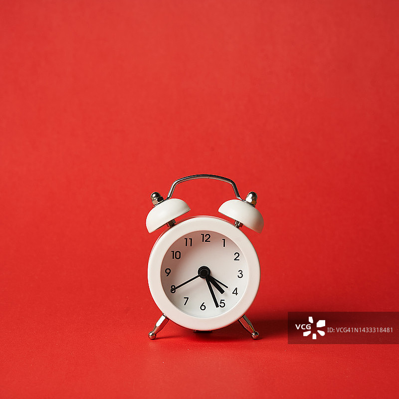 红色背景上的白色闹钟，凌晨4点26分，带留白的正面视图图片素材
