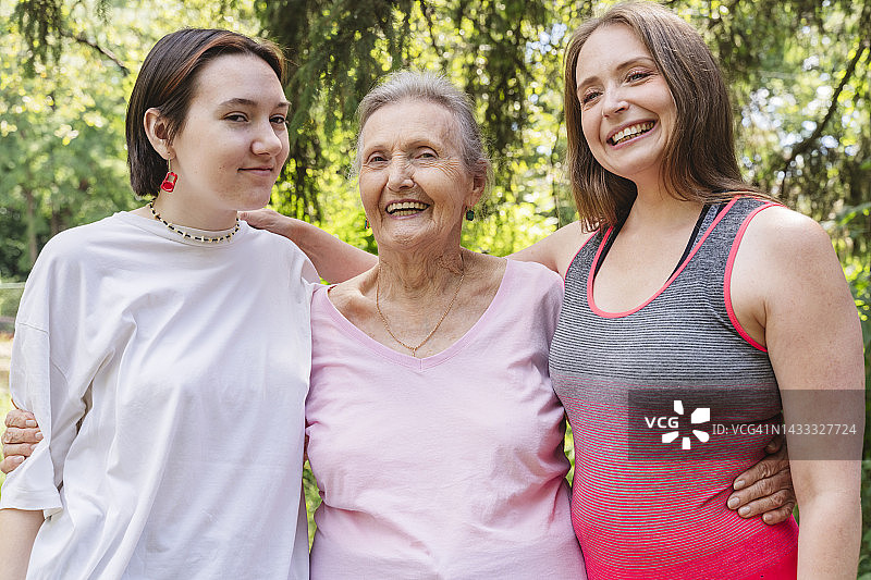 快乐的老年妇女与女儿和孙女站在公园里图片素材