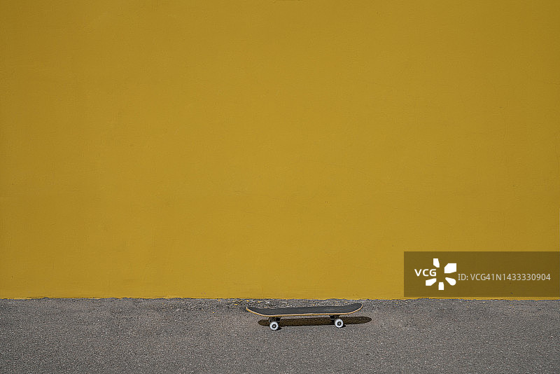 黄色墙壁前的滑板图片素材