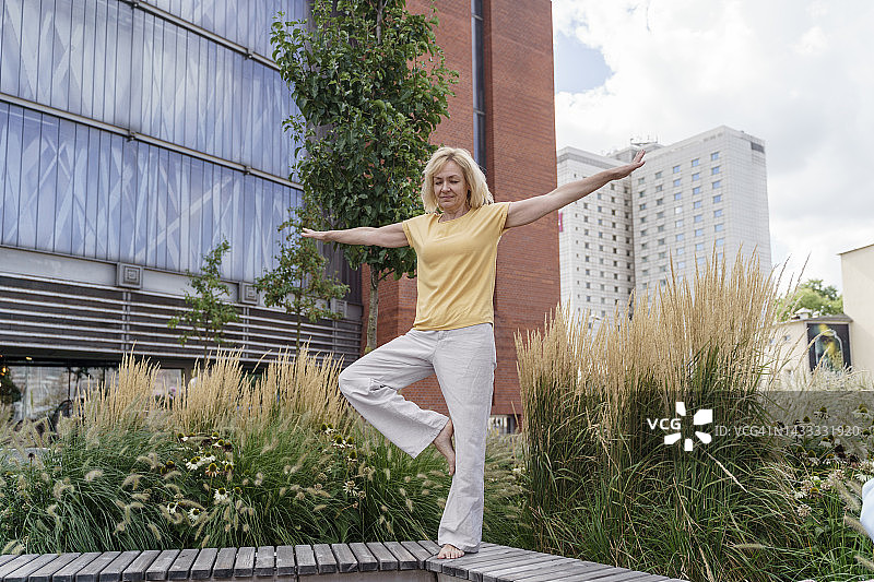 站在长椅上伸展双臂的中年妇女图片素材