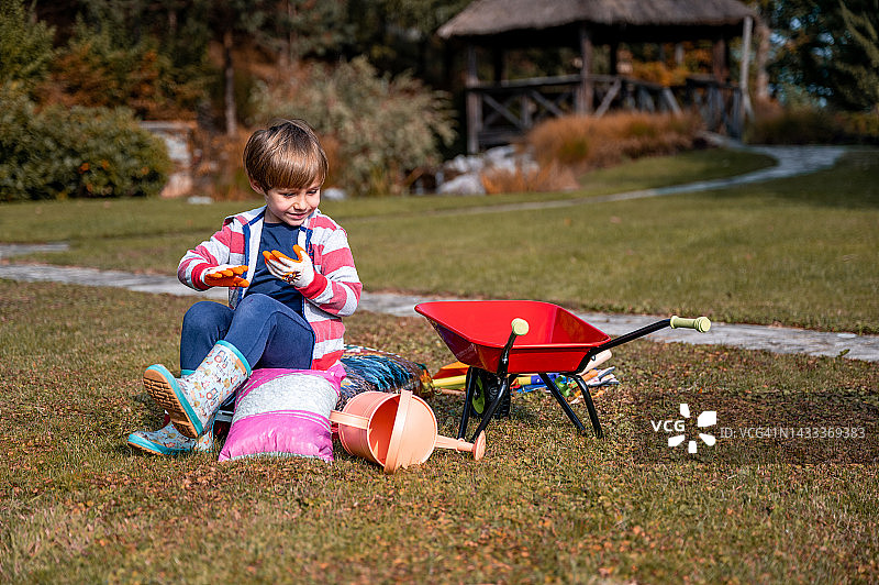 在花园里拿着儿童园艺设备的小男孩图片素材